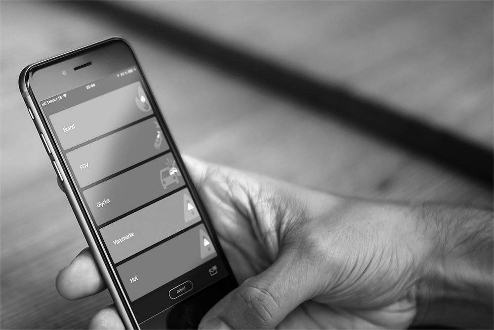 Hand håller en mobiltelefon som visar Cosafes larmapp, med funktioner för snabb och säker krishantering.